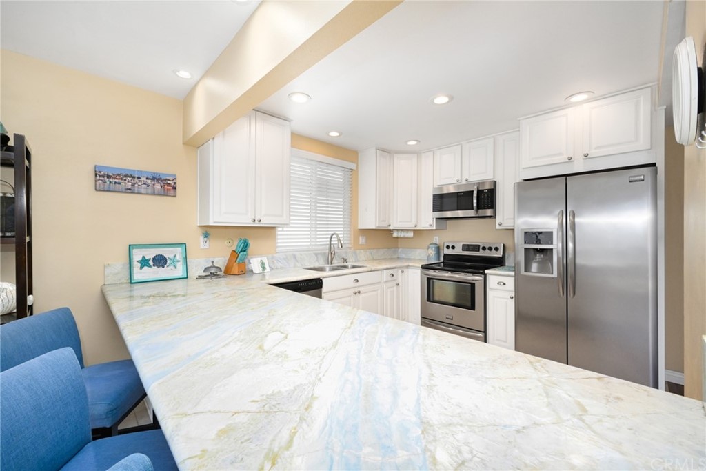 5100 Seashore Drive Newport Beach, CA 92663 - Photo 15 of 67 a kitchen with stainless steel appliances kitchen island granite countertop a refrigerator sink and stove