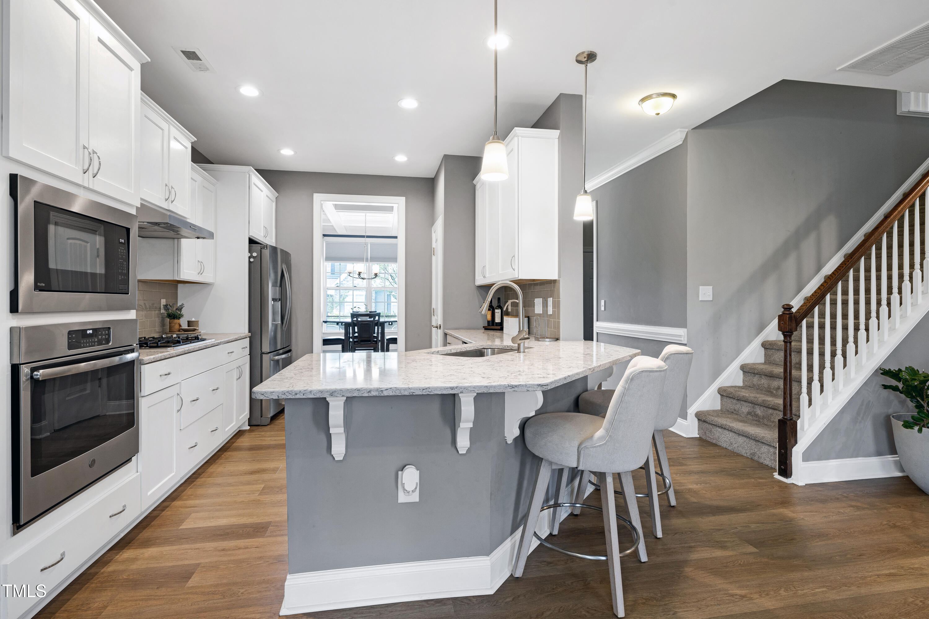 1417 Slate Ridge Road Knightdale, NC 27545 - Photo 12 of 66 a large kitchen with stainless steel appliances kitchen island granite countertop a stove a sink a refrigerator and a dining table with wooden floor