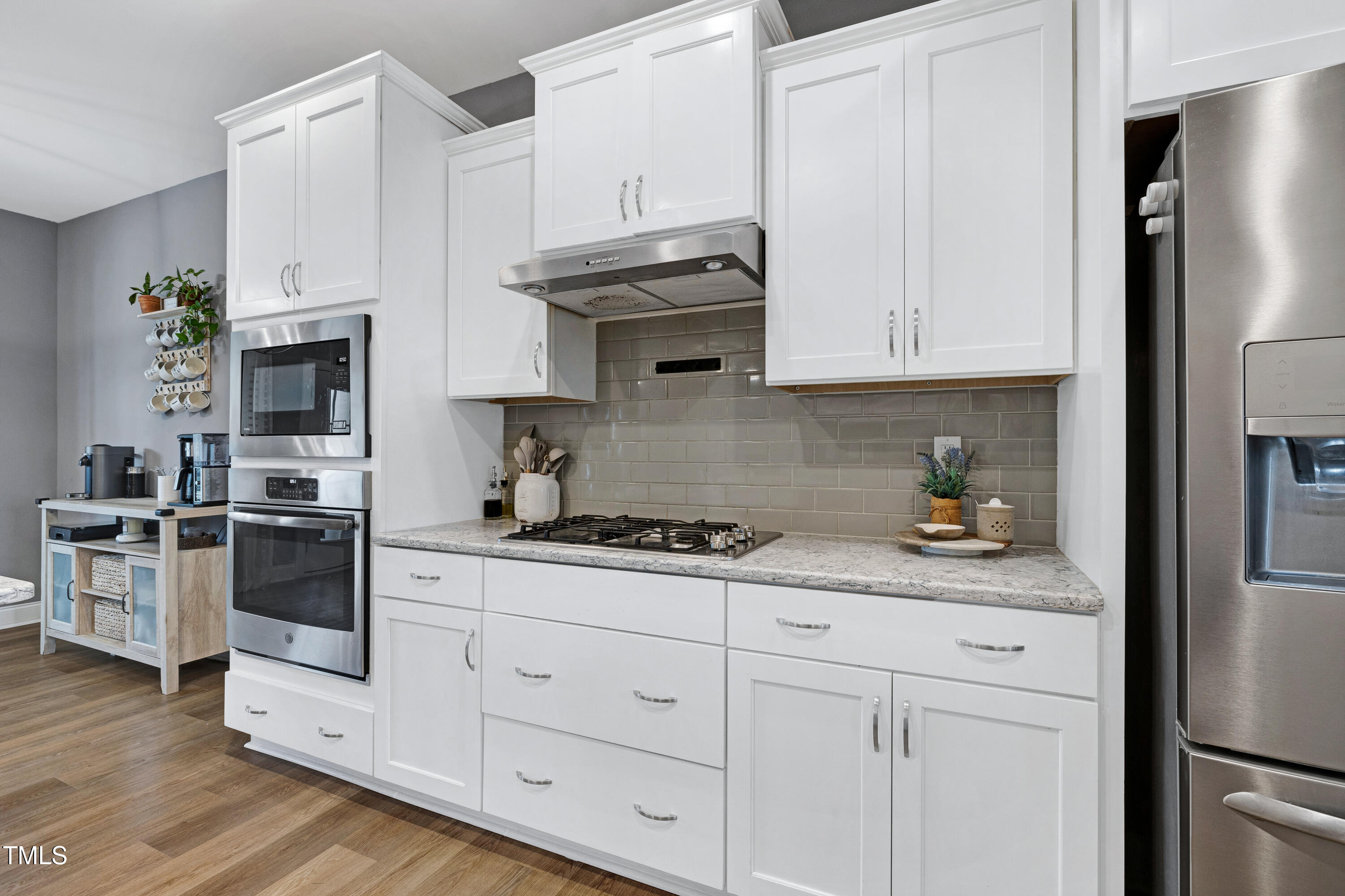 1417 Slate Ridge Road Knightdale, NC 27545 - Photo 15 of 66 a kitchen with stainless steel appliances granite countertop white cabinets and a stove a refrigerator with wooden floor