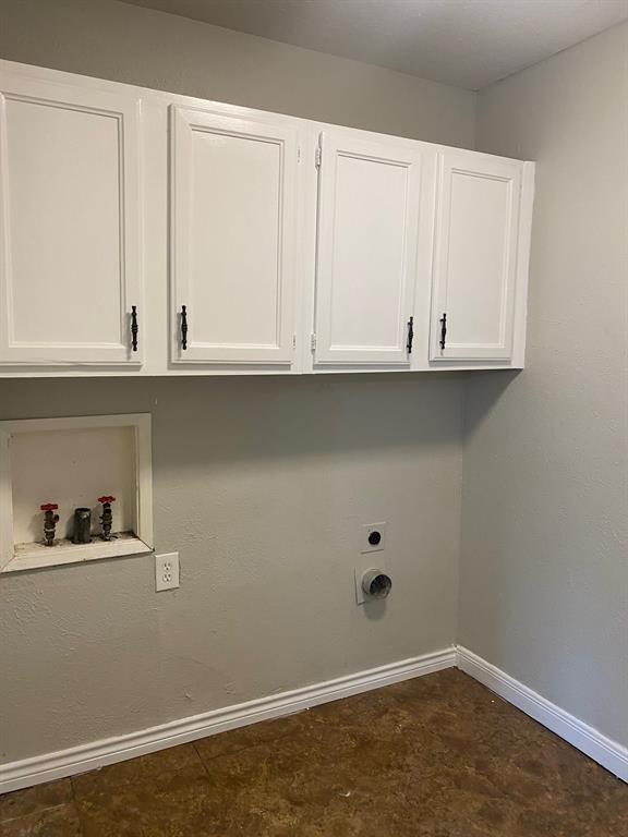 1109 Cross Bend Road Plano, TX 75023 - Photo 11 of 11 Utility area featuring upper white cabinetry with dark hardware, a laundry hookup recess, and a floor drain, all complemented by a light-toned wall finish and wood-finish flooring
