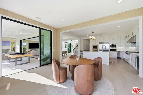 a view of a dining room with furniture a chandelier and large windows