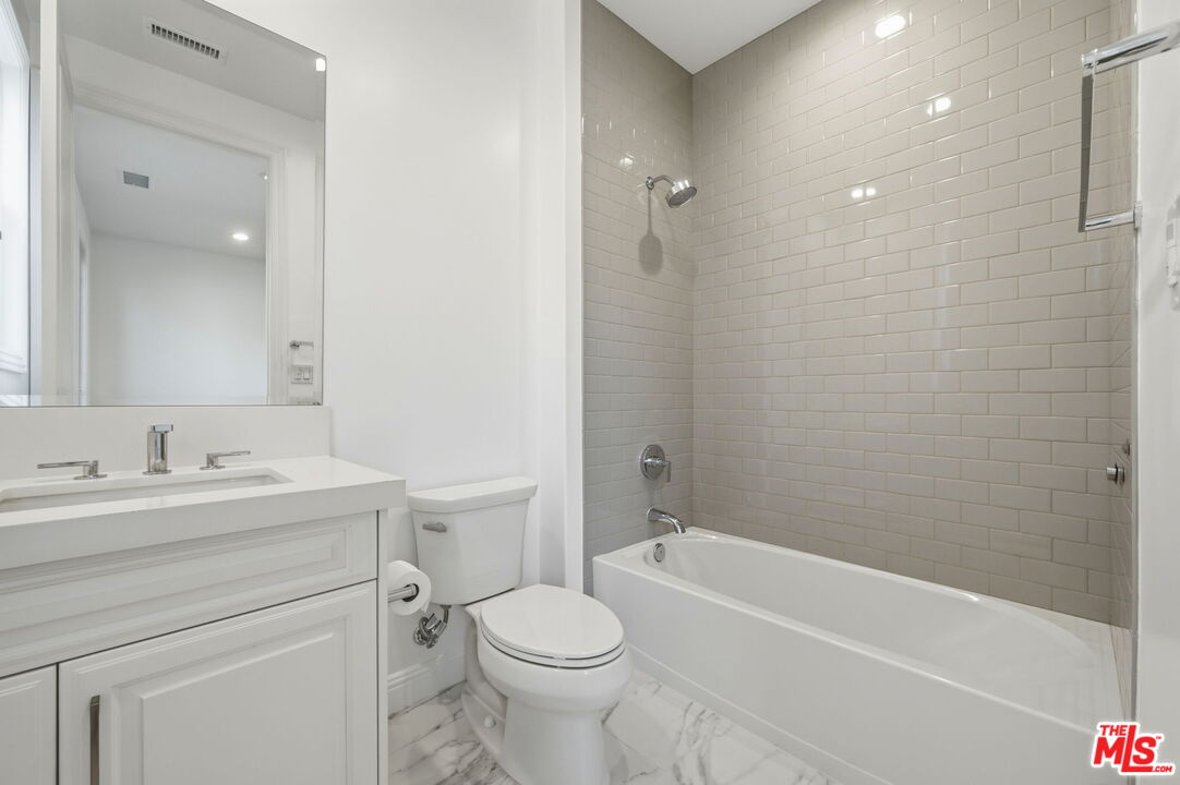 20448 Liverpool Way Porter Ranch, CA 91326 - Photo 37 of 61 a bathroom with a toilet a sink a mirror a bathtub and vanity