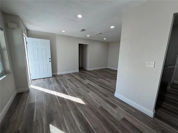 a view of an empty room with wooden floor and stairs