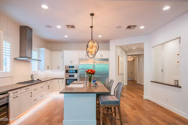 a kitchen with kitchen island granite countertop a sink a stove and a wooden floors