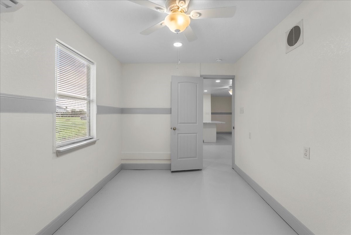 515 Thunder Road Surfside Beach, TX 77541 - Photo 14 of 31 This room is bright and airy, featuring light-colored walls and flooring. It has a ceiling fan, a window for natural light, and leads to another area of the house, suggesting a connected layout.