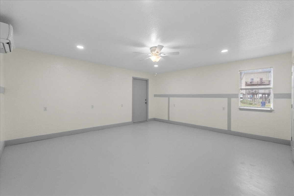 515 Thunder Road Surfside Beach, TX 77541 - Photo 22 of 31 This is a spacious, neutral-toned room with a ceiling fan and recessed lighting. It features a window for natural light and a door leading outside. The minimalistic design offers a versatile space for various uses.