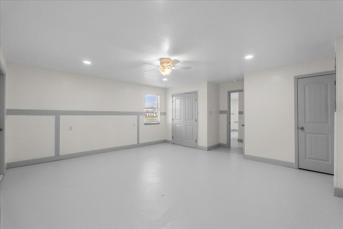 515 Thunder Road Surfside Beach, TX 77541 - Photo 24 of 31 The photo shows a spacious, light-filled room with neutral walls and flooring. It features recessed lighting, a ceiling fan, and multiple doors, good connectivity to the other areas. The room has a simple and modern look, ideal for versatile use.