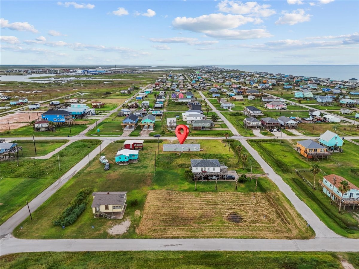515 Thunder Road Surfside Beach, TX 77541 - Photo 30 of 31 This aerial photo showcases a charming coastal community with colorful houses, open green spaces, and proximity to the water. The highlighted property is centrally located within this picturesque neighborhood, perfect for those seeking a serene, seaside lifestyle.