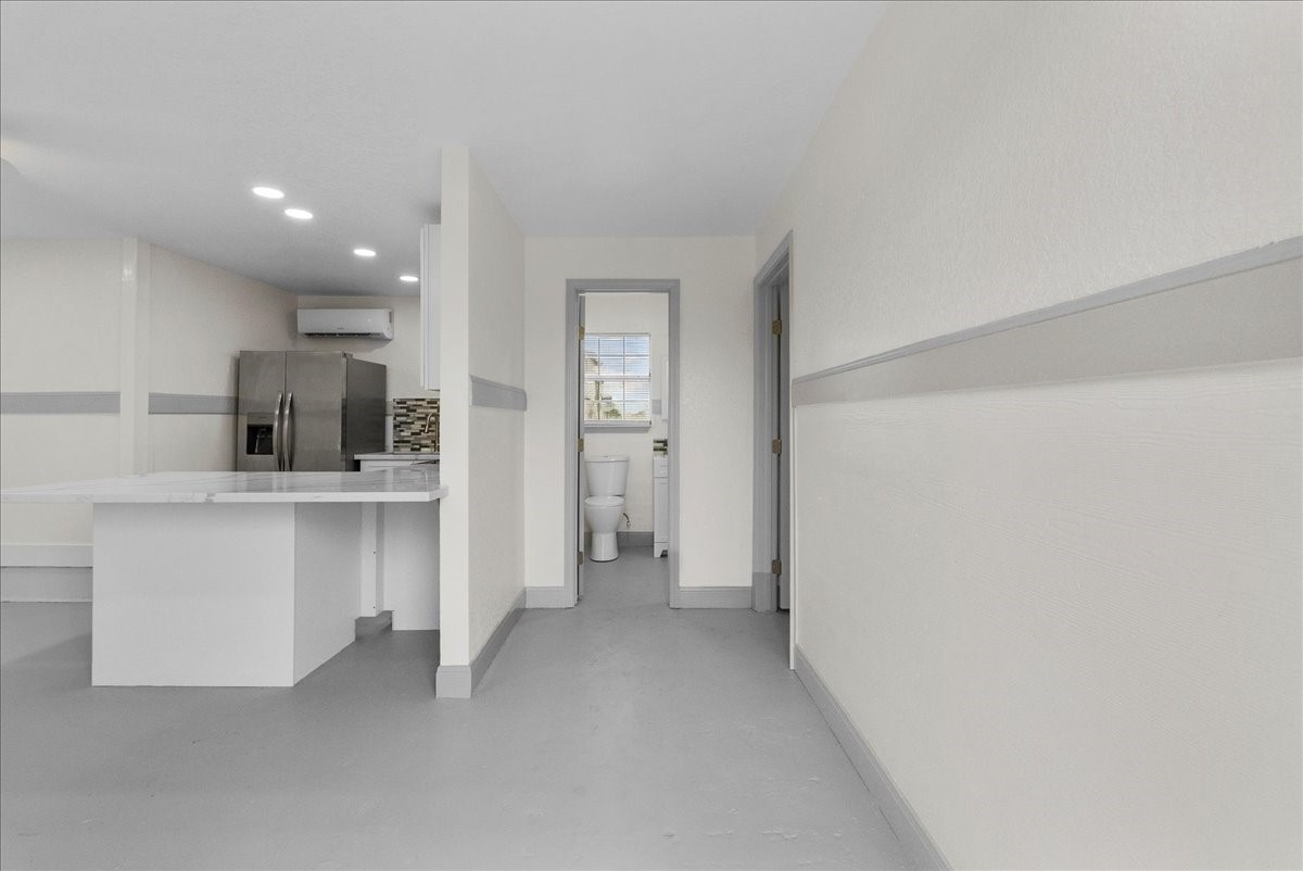 515 Thunder Road Surfside Beach, TX 77541 - Photo 5 of 31 Bright, modern kitchen with stainless steel appliances and sleek white countertops, adjacent to a hallway leading to bathroom. Ideal for a contemporary lifestyle.