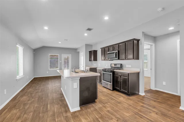 a living room with stainless steel appliances granite countertop wooden floor sink stove and wooden floor