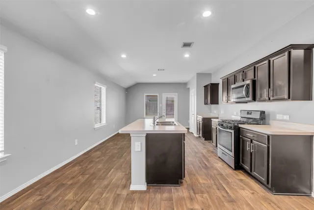 a kitchen with stainless steel appliances granite countertop a stove a sink dishwasher and a microwave oven with wooden floor