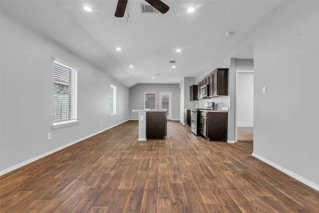 a kitchen with kitchen island a counter top space appliances and a ceiling fan