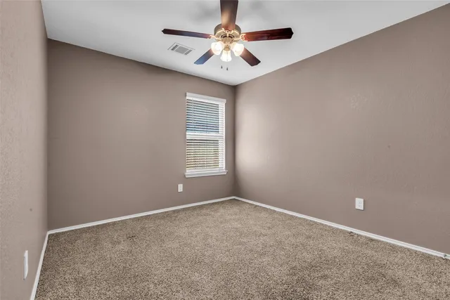 an empty room with a window and a fan