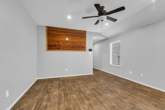 a view of an empty room with window and wooden floor