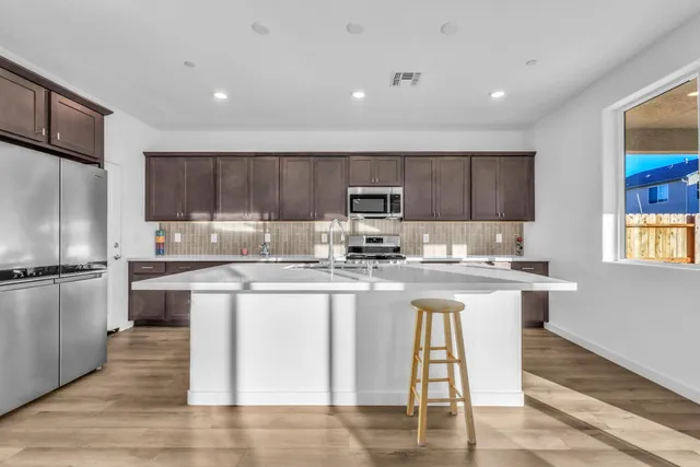 a kitchen with stainless steel appliances granite countertop a stove top oven a sink a refrigerator and white cabinets