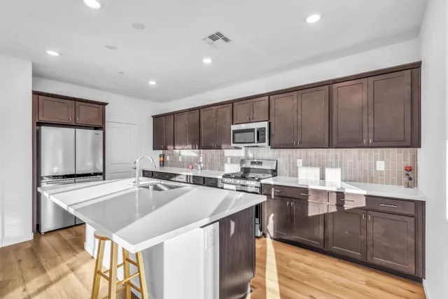 a kitchen with a sink a stove cabinets and wooden floor