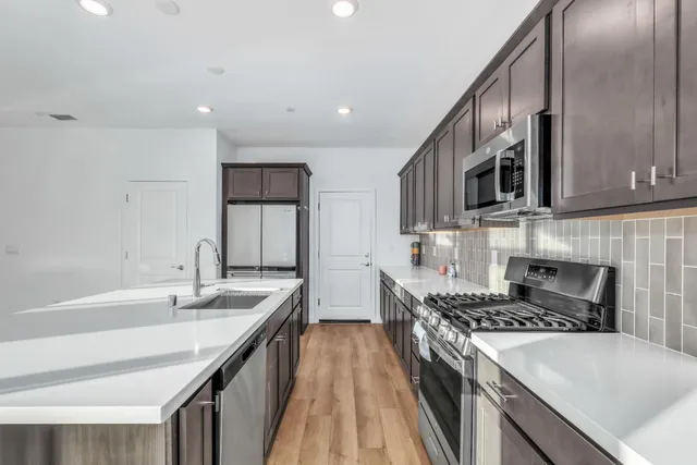 a kitchen with stainless steel appliances granite countertop a sink stove and refrigerator