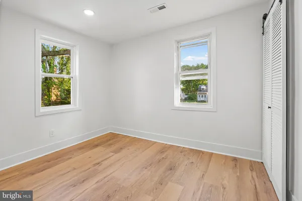 a view of an empty room with a window and wooden floor