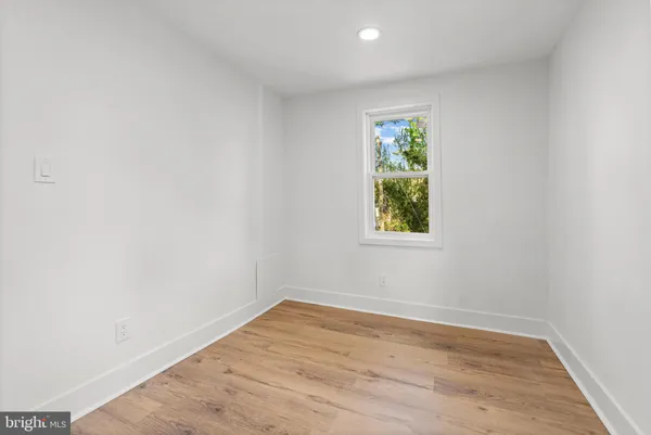 a view of a hallway with wooden floor and a bathroom