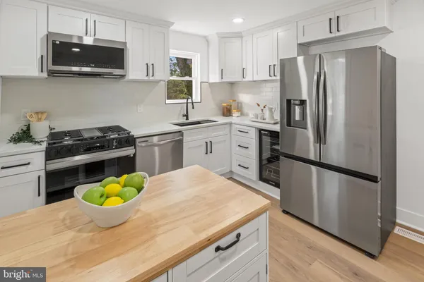 a kitchen with stainless steel appliances white cabinets and a wooden floor