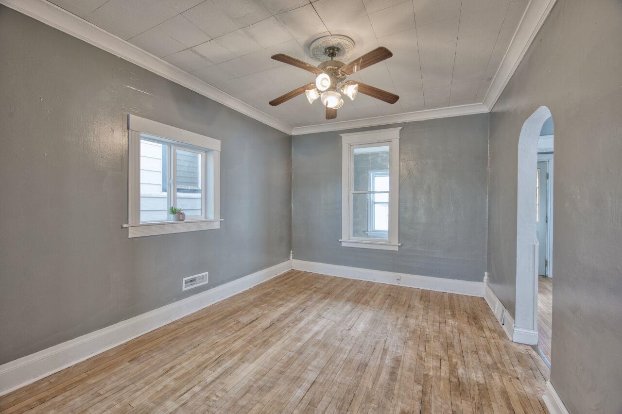 25 3rd Street Southwest Chisholm, MN 55719 - Photo 7 of 44 Unfurnished room with plenty of natural light, ornamental molding, light wood finished floors, arched walkways, and a ceiling fan