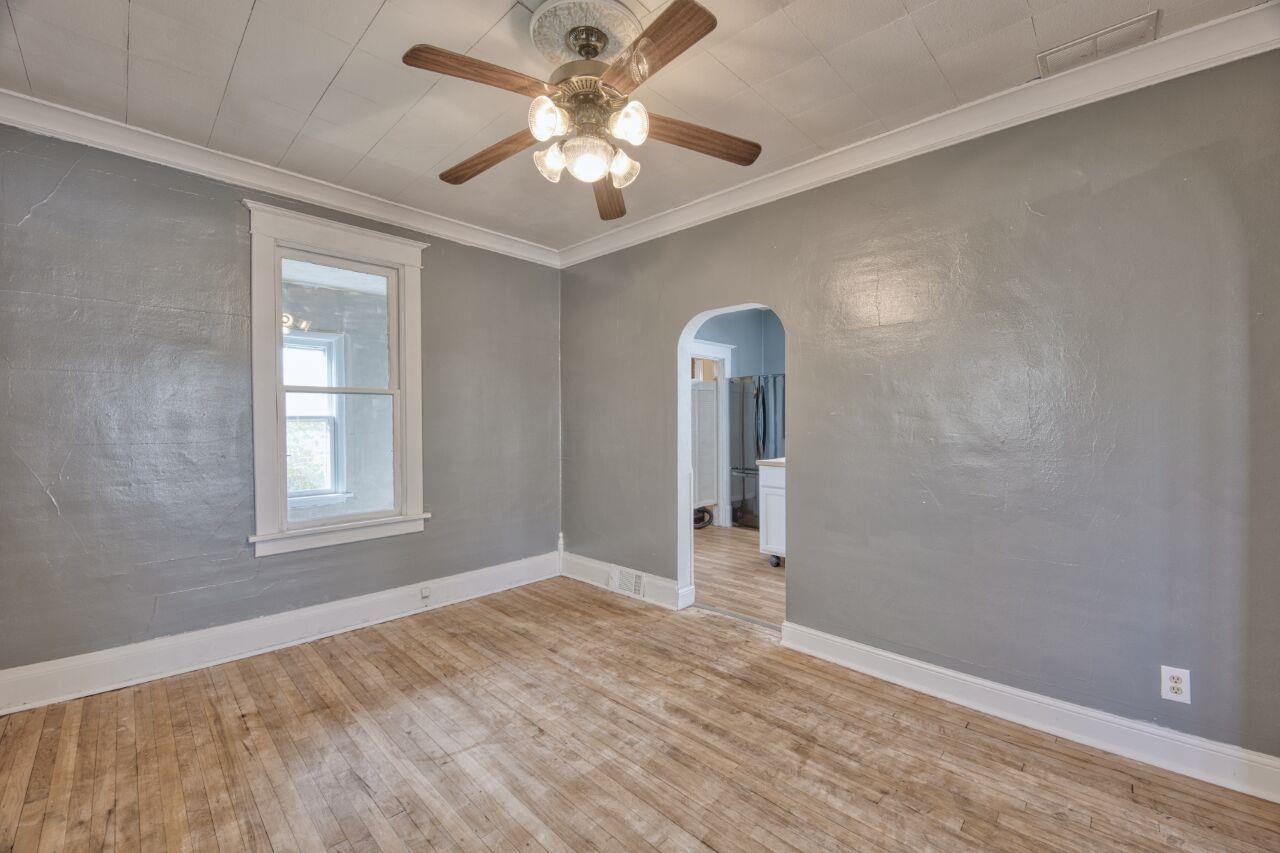 25 3rd Street Southwest Chisholm, MN 55719 - Photo 8 of 44 Unfurnished room featuring ornamental molding, light wood-style flooring, arched walkways, and a ceiling fan