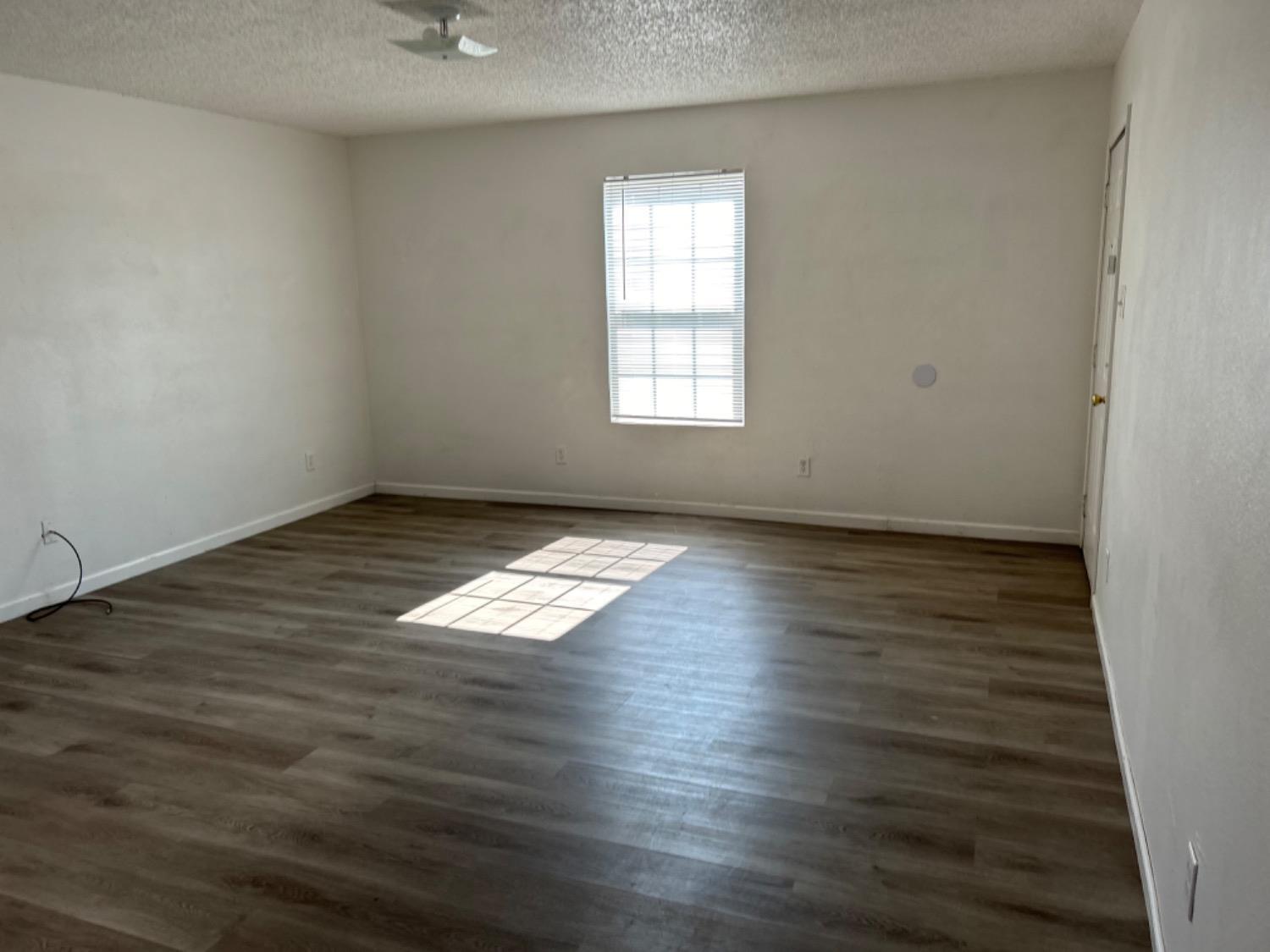 1508 82nd Street, Unit B Lubbock, TX 79423 - Photo 3 of 8 an empty room with wooden floor and windows