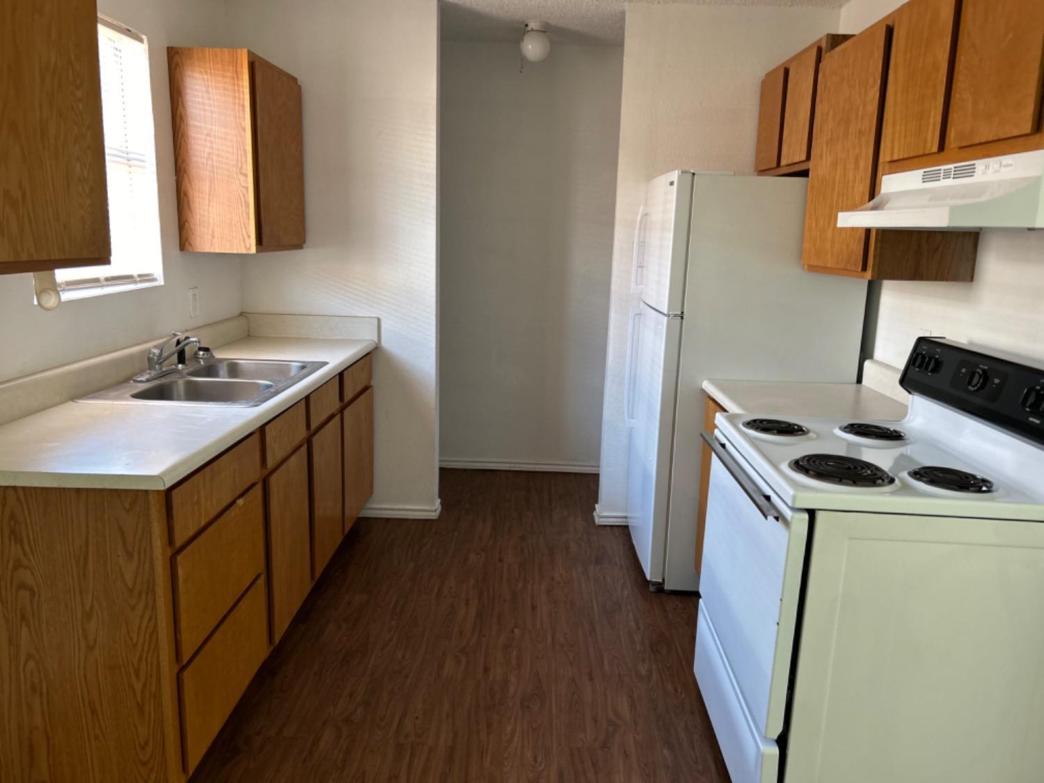 1508 82nd Street, Unit B Lubbock, TX 79423 - Photo 7 of 8 a kitchen with a sink a refrigerator a stove and wooden floor