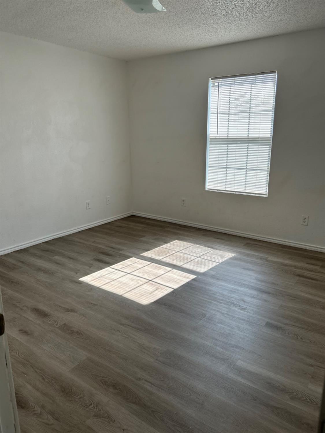 1508 82nd Street, Unit B Lubbock, TX 79423 - Photo 8 of 8 an empty room with wooden floor and windows