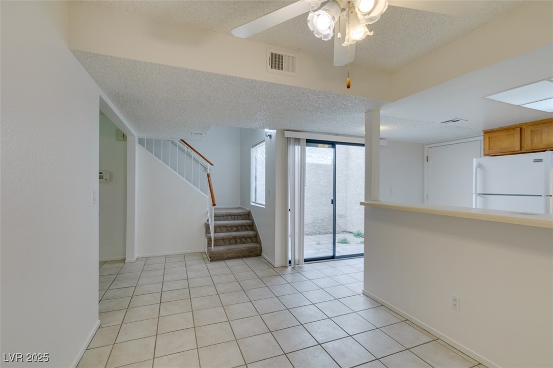 2681 Ruthe Duarte Avenue Las Vegas, NV 89121 - Photo 19 of 43 Unfurnished room with visible vents, stairs, light tile patterned flooring, and a textured ceiling