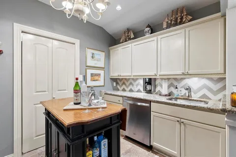 a kitchen with stainless steel appliances kitchen island granite countertop a refrigerator a stove top oven a dining table and chairs with wooden floor