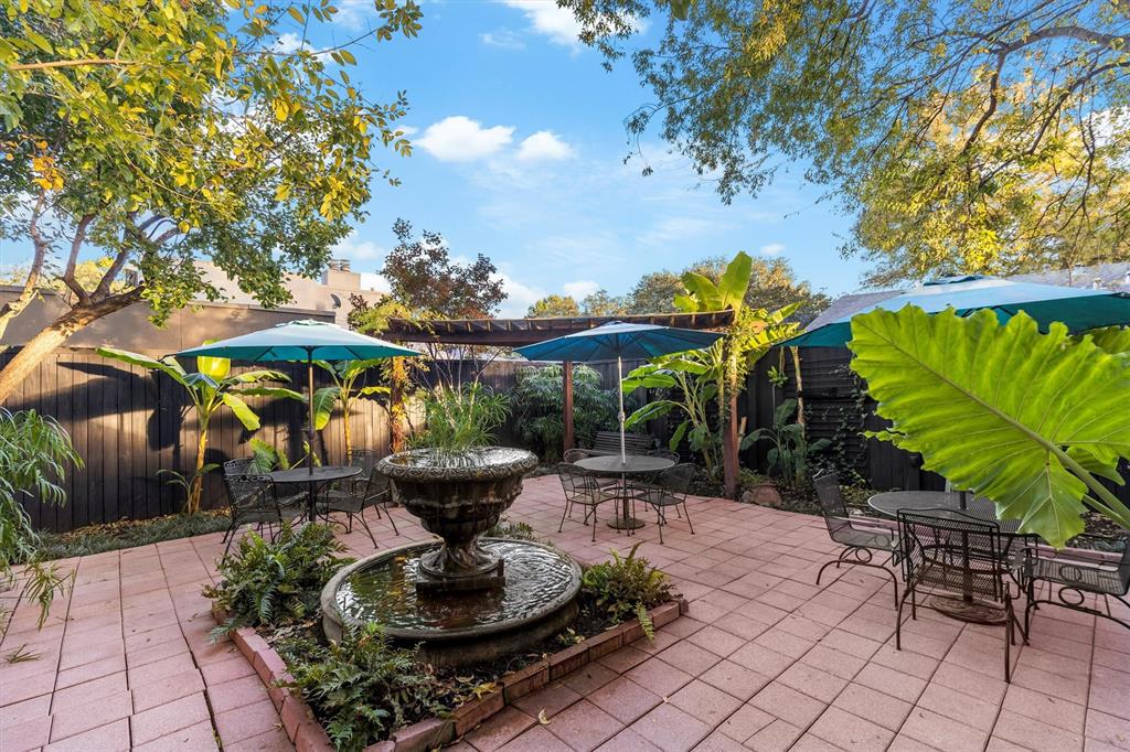 1432 Sylvan Avenue Dallas, TX 75208 - Photo 39 of 40 a view of a backyard with plants and a table and chairs under an umbrella with a fire pit