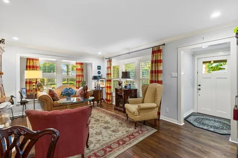 a living room with furniture a rug a fireplace and a floor to ceiling window