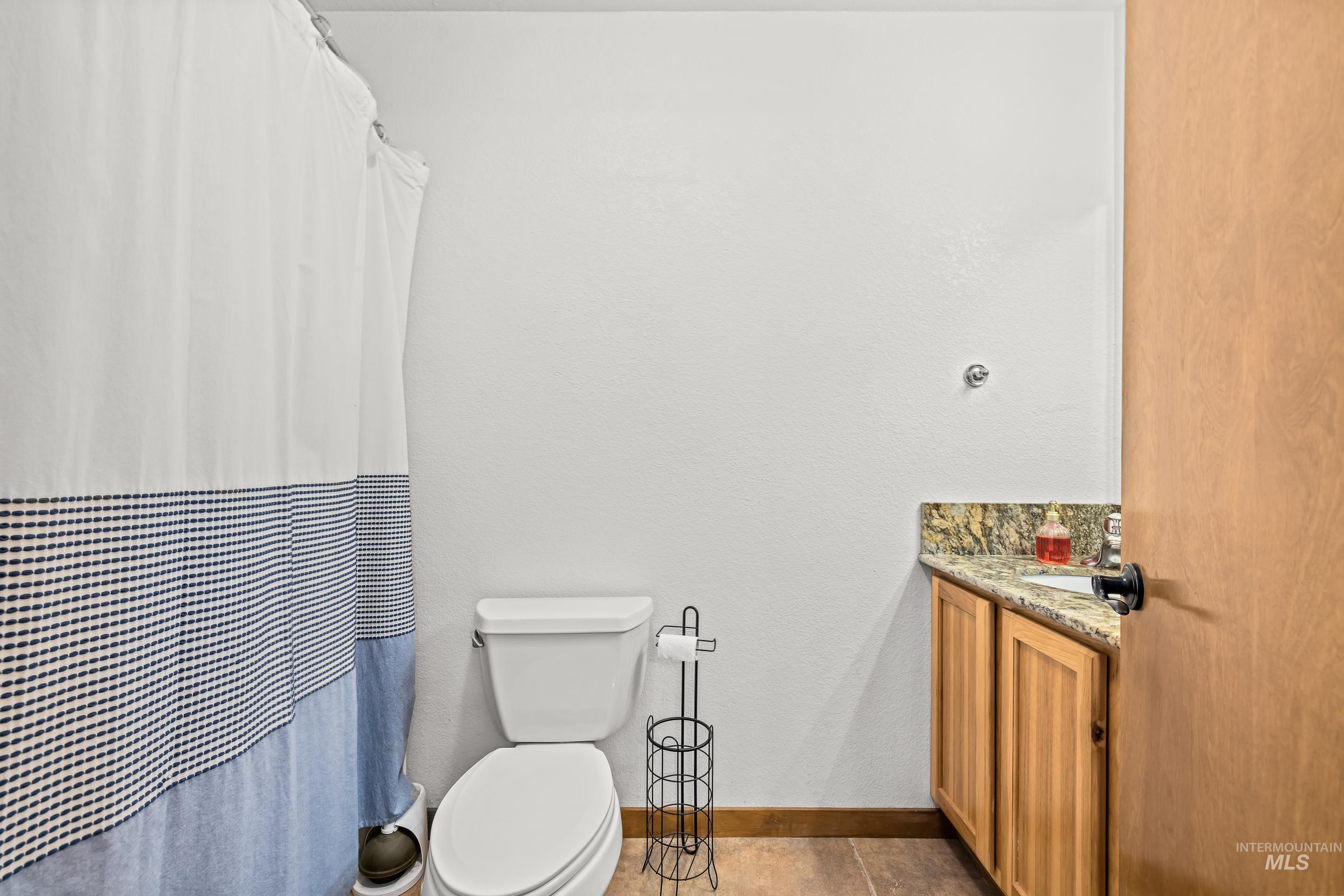 92 Cruickshank Road Horseshoe Bend, ID 83629 - Photo 36 of 50 Bathroom featuring a toilet, a light wood vanity with a granite countertop, and tile flooring