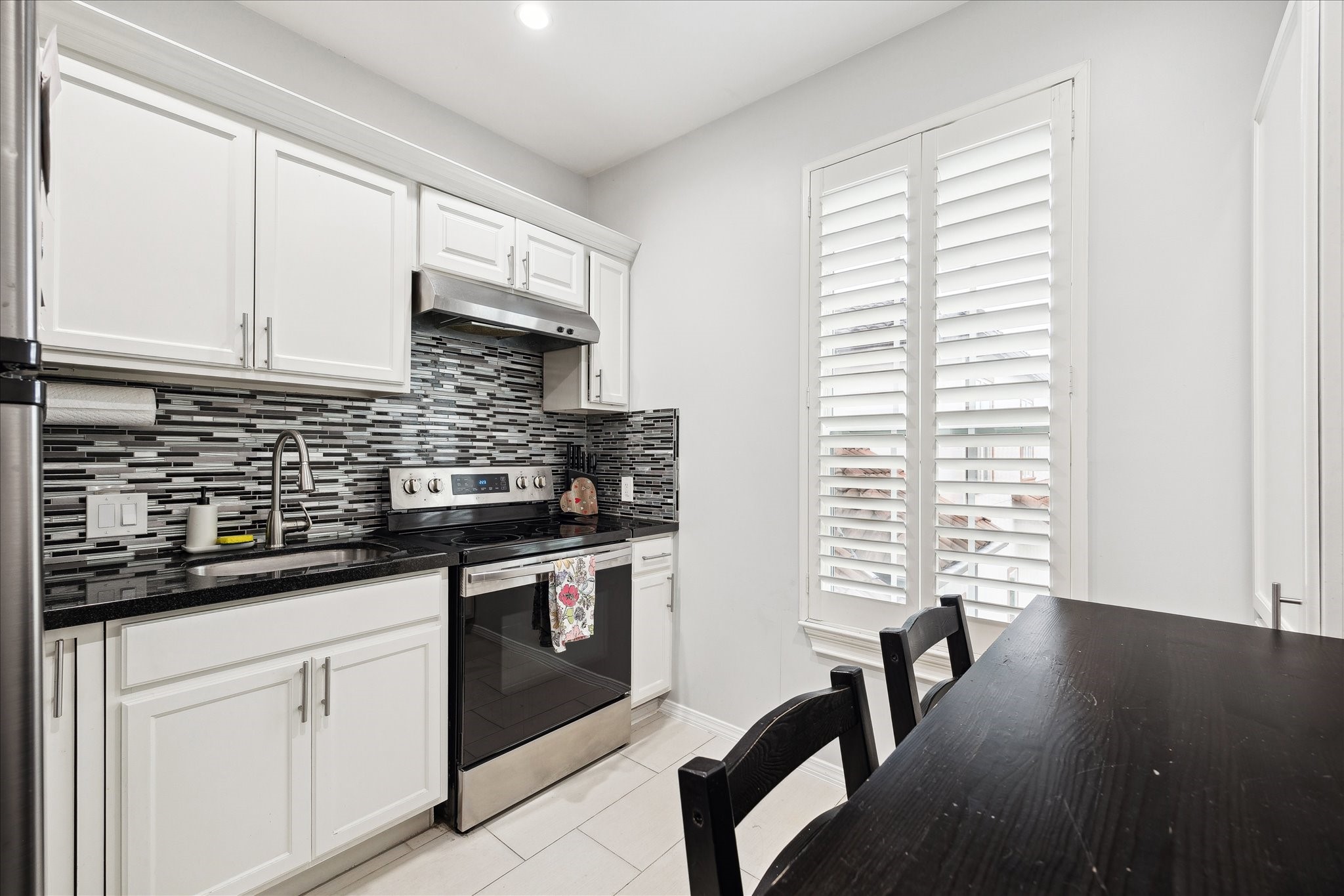 8917 Hawk Road Pearland, TX 77584 - Photo 25 of 33 a kitchen with stainless steel appliances granite countertop white cabinets a sink a stove a dining table and chairs