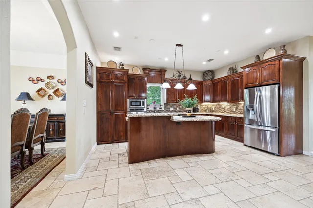 a kitchen with stainless steel appliances granite countertop a refrigerator a sink a stove a oven and a refrigerator
