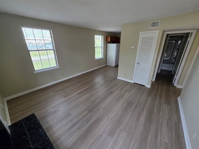 a view of an empty room with wooden floor and a window