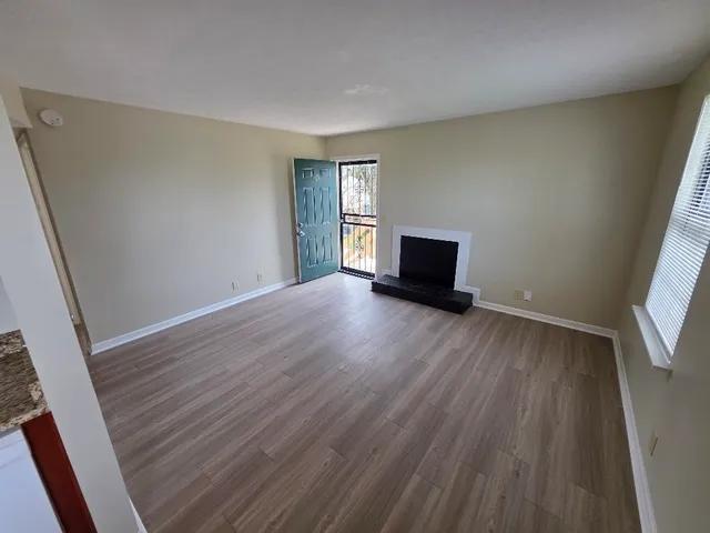 an empty room with wooden floor and windows