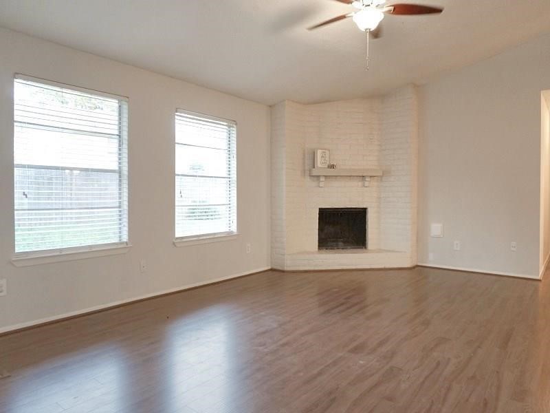 16210 Cypress Point Drive Cypress, TX 77429 - Photo 4 of 10 an empty room with wooden floor fireplace and windows