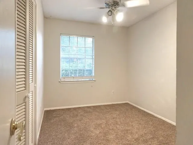 an empty room with a chandelier fan and windows