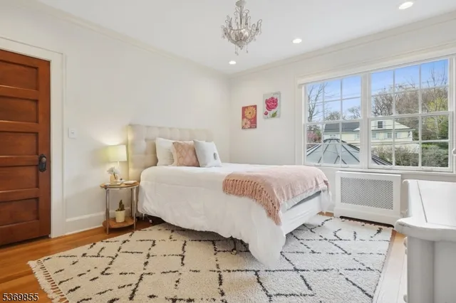 a bedroom with a bed a clock and a bookshelf with wooden floor