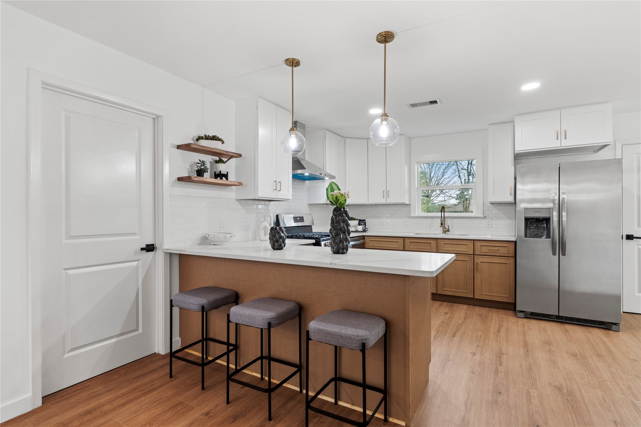 5023 Redstart Street Houston, TX 77035 - Photo 14 of 34 Beautifully designed with two-toned cabinetry and quartz countertops, this kitchen offers ample prep space and a bright window overlooking the outdoors.