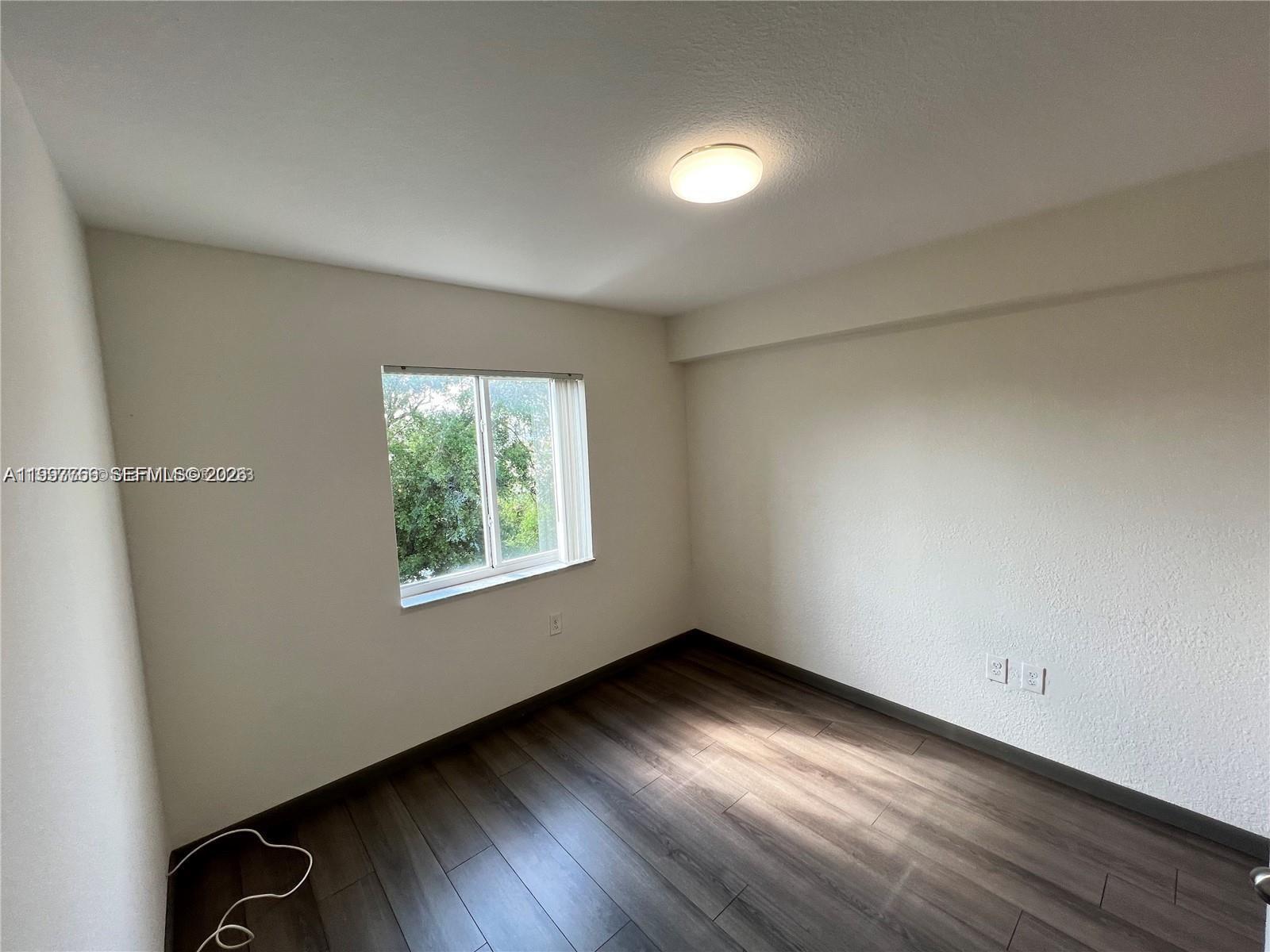 637 Southwest 3rd Street, Unit 306 Miami, FL 33130 - Photo 13 of 19 a view of an empty room with wooden floor and a window