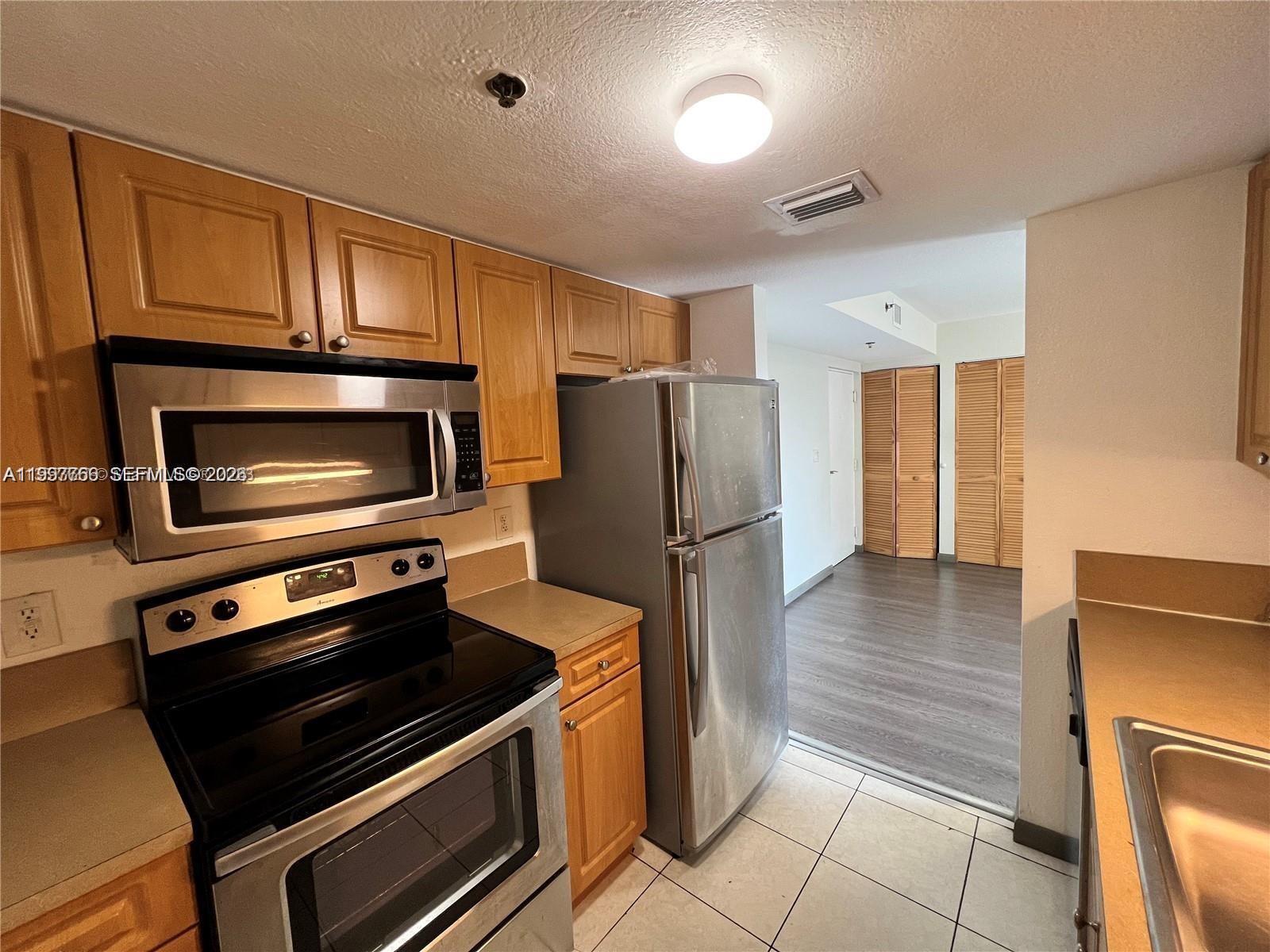 637 Southwest 3rd Street, Unit 306 Miami, FL 33130 - Photo 8 of 19 a kitchen with granite countertop a refrigerator and a stove top oven
