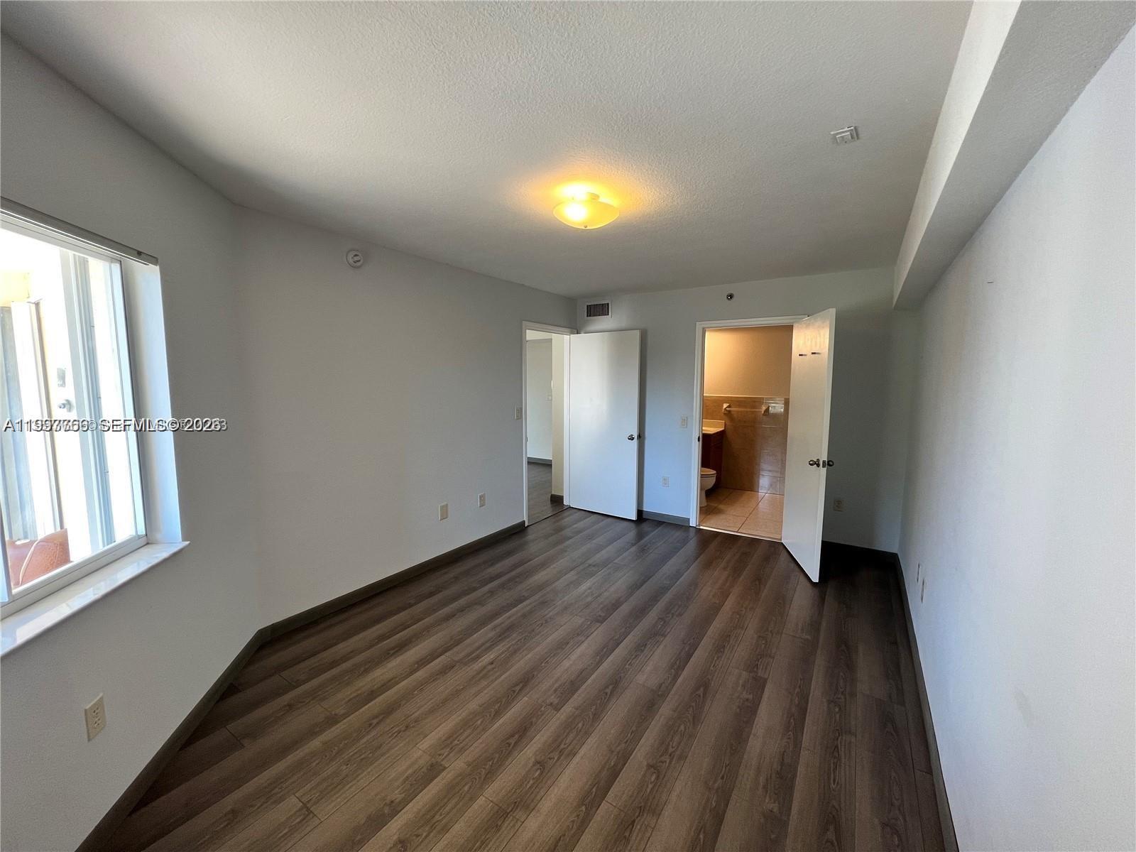 637 Southwest 3rd Street, Unit 306 Miami, FL 33130 - Photo 10 of 19 a view of an empty room with wooden floor and a window