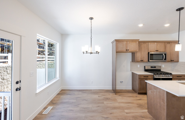 4809 Olive Avenue, Unit 417 Mapleton, UT 84664 - Photo 5 of 18 Kitchen with light wood-type flooring, stainless steel appliances, hanging lights, wood finish cabinets, and light stone countertops