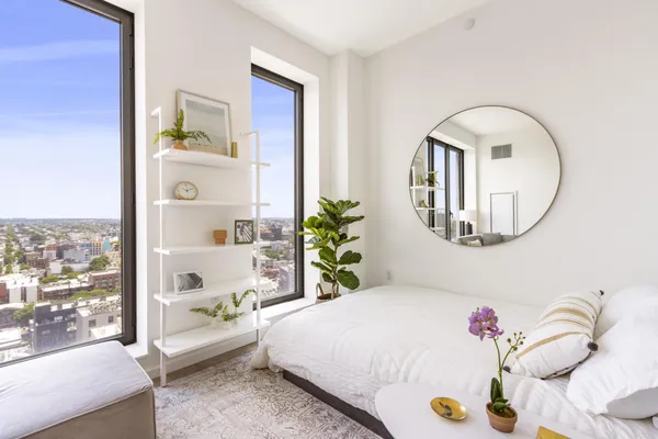 a bedroom with a bed a mirror and a potted plant