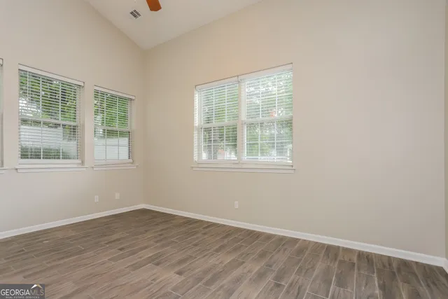 an empty room with wooden floor and windows