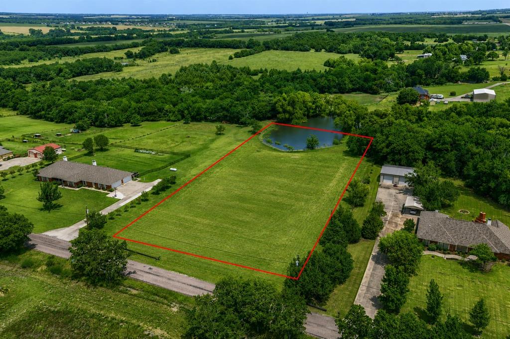 Expansive grassed lot featuring a private pond and bordering mature trees