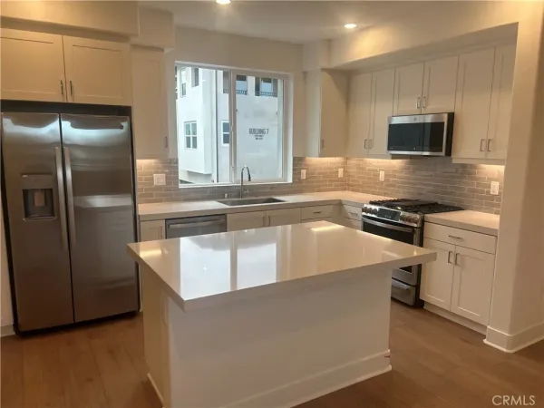 a kitchen with stainless steel appliances granite countertop a refrigerator a stove and a sink with wooden floor